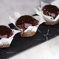 chocolate cake wrapped in cake paper with chocolate glaze topping