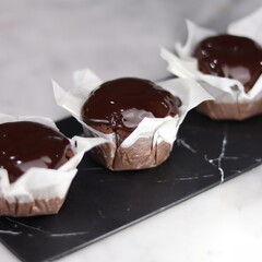 chocolate cake wrapped in cake paper with chocolate glaze topping