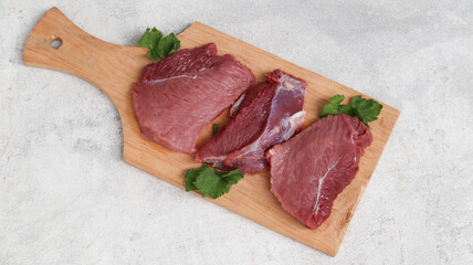 Fresh raw meat at wooden cutting board isolated on grey