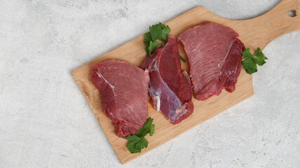 Fresh raw meat at wooden cutting board isolated on grey