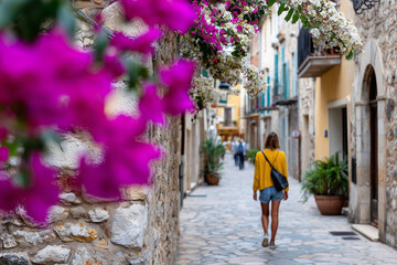 solo woman walking down Mediterranean street with stone walls and flowers, 