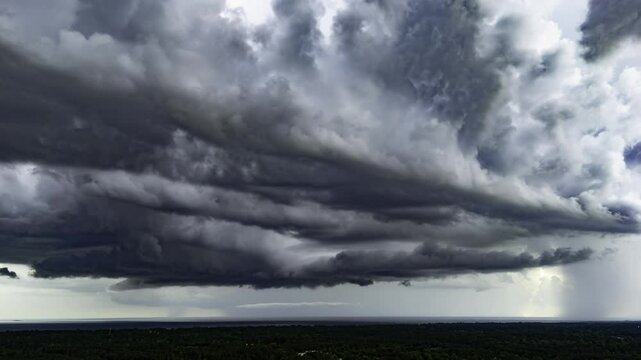 Ominous dark storm clouds slowly roll across the sky, signaling an approaching storm. The dramatic motion and shifting layers of cloud formations create a tense, foreboding atmosphere.