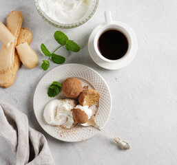 Tiramisu balls with whipped cream on the white plate with coffe nearby. top view, copy space
