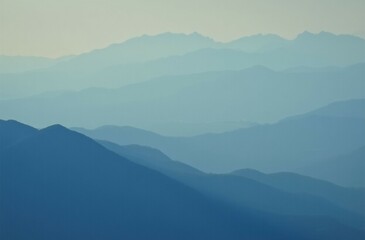 Fototapeta premium Minimalist landscape of layered mountain ranges in the distance, with soft blue and teal color tones
