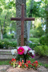 Christian Wooden Cross on Grave with Colorful Flowers – Peaceful Memorial Scene in Nature. Grave Cross with Bright Peonies and Begonias – Spiritual Symbol of Hope