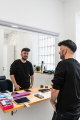 Hairdresser presenting a hair replacement system to a client in front of a mirror in a hair salon
