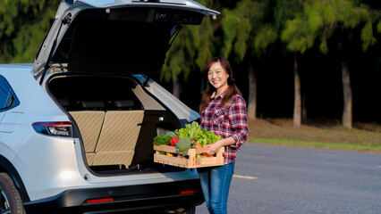 Smiling female farmer loading fresh organic vegetables into the car trunk, symbolizing sustainable farming and local produce transportation from farm to market