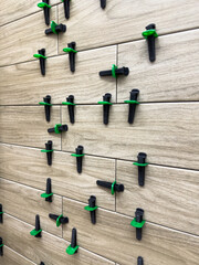 Close up of wall tiles being aligned with reusable leveling system. The spacers help achieve a...