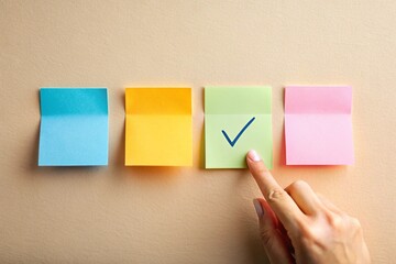 Colorful sticky notes arranged in a row with a hand pointing to a green note marked with a checkmark symbolizing task completion and organization on