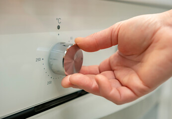 Adjusting the temperature on an oven dial for optimal cooking in a modern kitchen setting