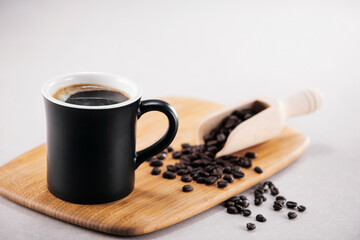 검은색 머그컵에 담긴 따듯한 커피와 원두.