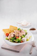 건강하고 균형잡힌 식사로 인기있는 닭가슴살, 치즈, 빵, 토마토와 견과류,야채로 만든 치킨 시저 샐러드.