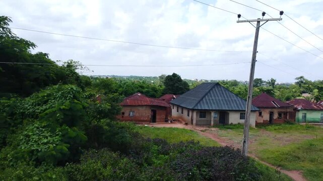 Pullback aerial revealing metal-roof homes and wires across urban Ibadan neighborhood