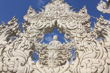 Looking Up White Temple Sculpture. Dramatic upward view of detailed Thai carvings and mirrored motifs at Wat Rong Khun.