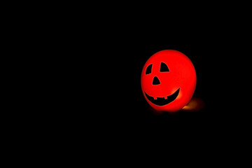 Glowing Halloween Balloon with Jack O Lantern Face on Black Background, copy space