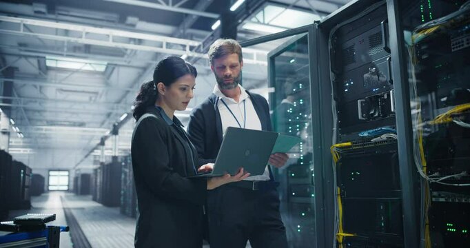 Tech Entrepreneur and Female Software Developer Talking while Running Diagnostics Software on Computer Devices Inside a Modern Data Center. Manager Explaining AI Infrastructure Features