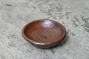 Close up view of empty little pottery plate. grey or gray cement as background. Copy space, empty space, free space for food photo. antique.
