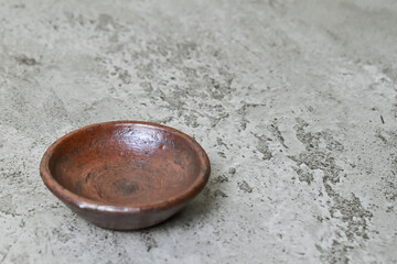 Close up view of empty little pottery plate. grey or gray cement as background. Copy space, empty space, free space for food photo. antique.