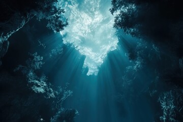 Fototapeta premium View from deep underwater showing sunlight breaking through the ocean surface with rays illuminating the dark depths, A view up to the ocean surface from deep underwater