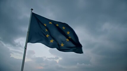 European Union flag waving against dark cloudy sky, symbolizing unity and cooperation - Powered by Adobe