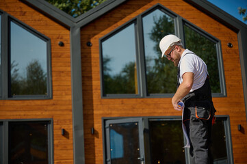 Architect hold plan. Bearded architect wearing hardhat holding project blueprints paper plans...