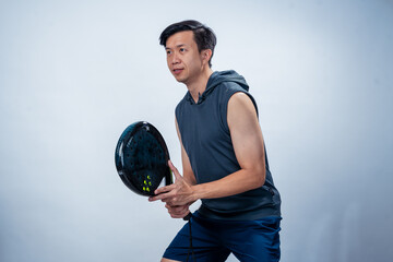 Asian man in sleeveless hoodie and shorts holding black padel racket in ready position, focused and...