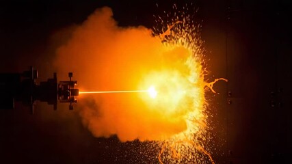 Explosive orange burst from laser impact in dark setting