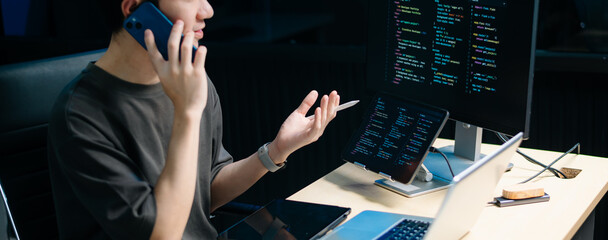 Male programmer using stylus to analyze code on tablet and monitor. Software development, coding,...