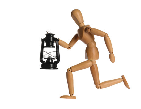 Wooden mannequin figure running, holding an antique oil lantern, isolated on white.