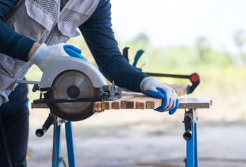 Carpenter Cutting Wood with Circular Saw on Workbench