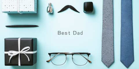 Flat lay of gifts and accessories for Father's Day. Includes ties, glasses, a gift box, and a note saying 'Best Dad'.
