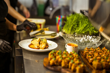 Gourmet dish being prepared in a professional kitchen, with microgreens, creamy sauce, and appetizers on the side, capturing the artistry of fine dining cuisine.