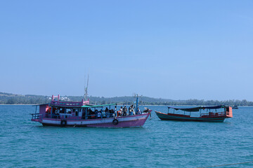 Obraz premium Passenger boat and small fishing boat on calm ocean water