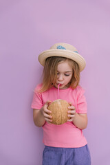 Young child enjoys a refreshing coconut drink while wearing a summer hat