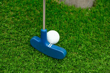 Close-Up of Blue Golf Putter Hitting White Ball Bright Green Turf as A Concept of Good Aiming 