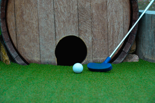 Close-Up of Mini Golf Putter and Ball by Wooden Barrel Course