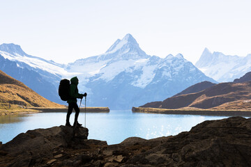 Silhouette of a backpacker against the Bachalpsee lake and snowy Swiss Alps mountains. Travel and adventure concept