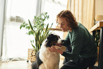 Young man enjoying a cozy moment at home with his loyal dog in a warm and inviting space