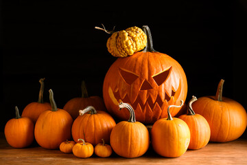 Scary jack-o'-lantern in center of tiny orange pumpkins on black background. Halloween-themed arrangement perfect for spooky decor and seasonal still life