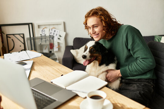 Young man enjoys a cozy moment at home with his pet dog and laptop on a sunny afternoon