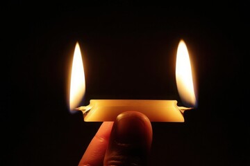 Burning at Both Ends: Close-up of a person's finger holding a small, lit candle with two flames against a black background.  Perfect for concepts of hope, remembrance, spirituality, and meditation.