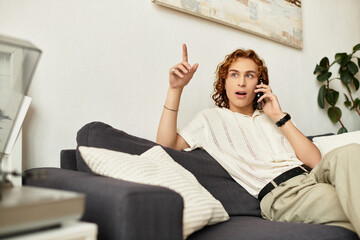 Young man relaxing at home while engaged in a lively conversation on his phone