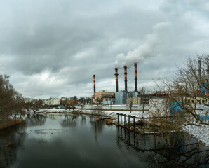 Industrial chimneys emit thick smoke into the winter sky, highlighting urban air pollution. A...