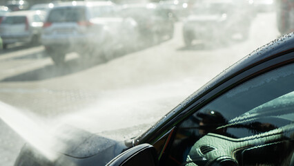 A self-service car wash featuring a high-pressure water spray cleaning a vehicle. Active foam...