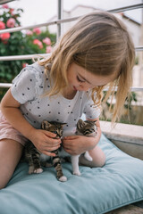 Young girl enjoys playful moments with kittens on a sunny afternoon outdoors