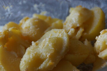 A generous plate of sliced potato salad, dressed in a light vinaigrette. Garnished with red onions, fresh parsley, and a drizzle of olive oil, the dish captures rustic simplicity and summer freshness.