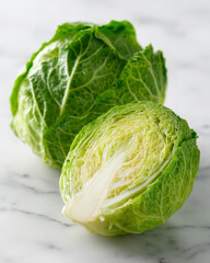 Fototapeta premium Fresh green cabbage cut in half, showcasing its vibrant leaves and texture on marble surface