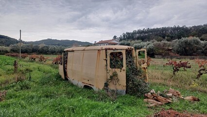 Vergessenes Auto-Wrack – Rostiges Chassis als Holzlager auf Feld