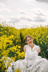 Woman enjoying a peaceful moment in a field of yellow flowers under a cloudy sky