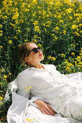 Woman relaxes in a field of yellow flowers on a sunny day in springtime